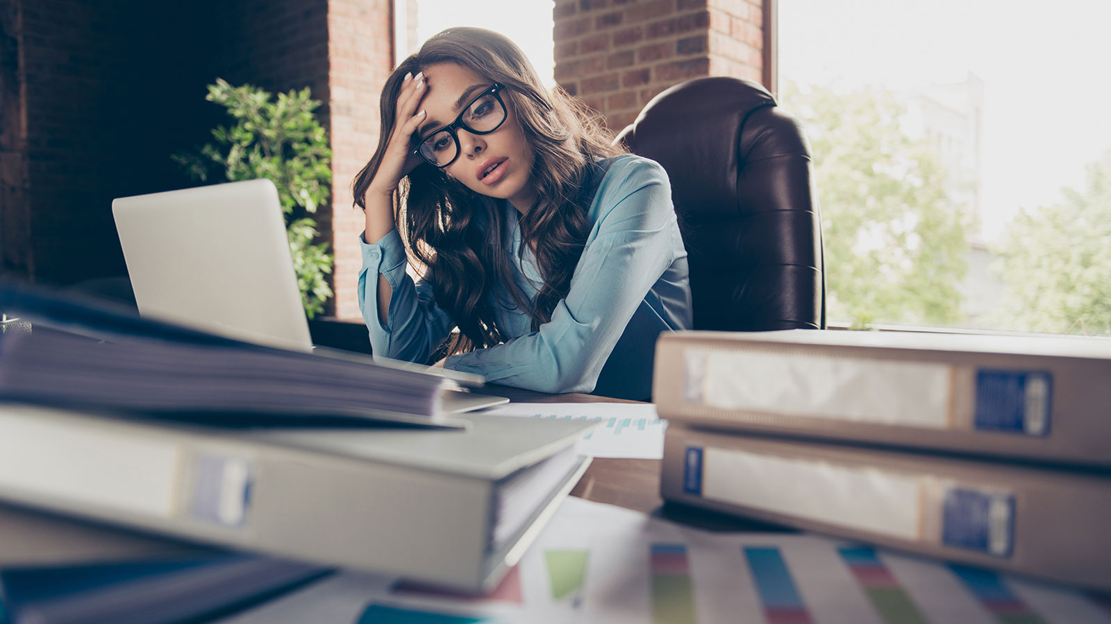 Tired women infront of a pile of folders