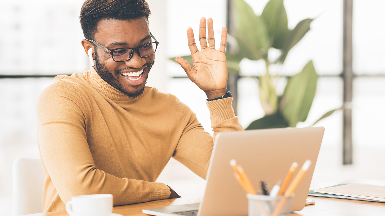 man waving at colleagues on his laptop