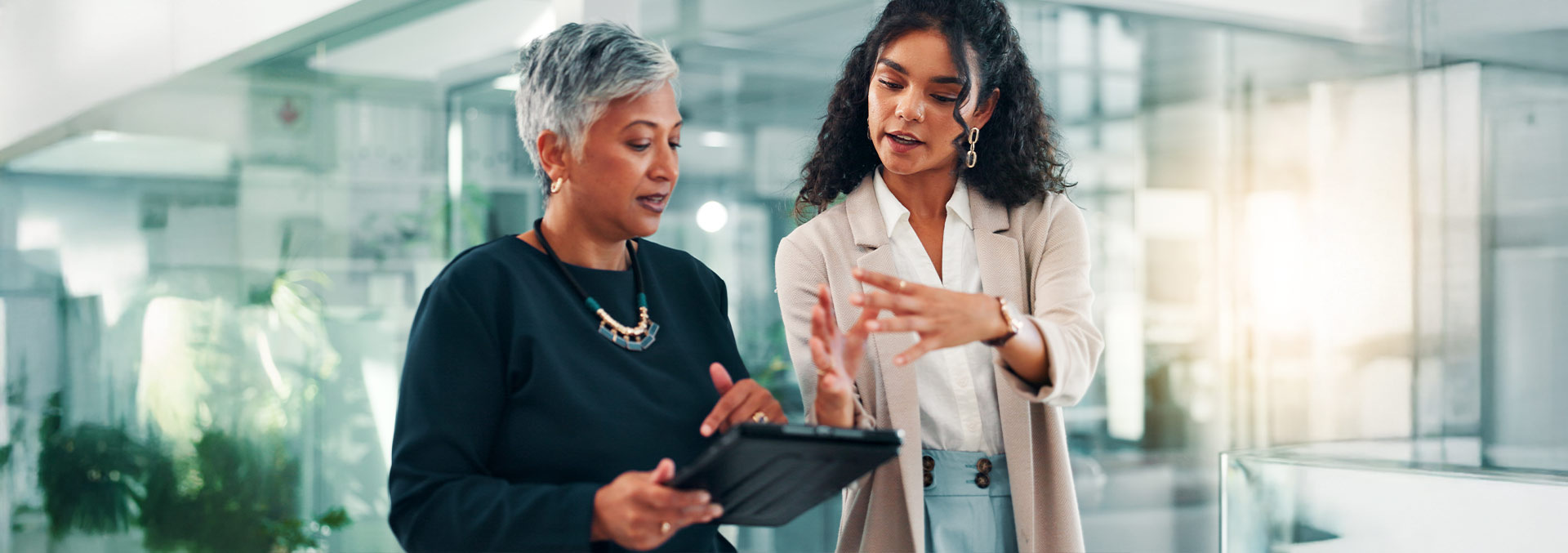 two women looking at information on a tablet together